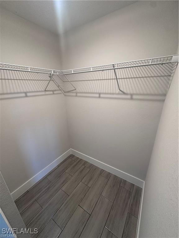 walk in closet with wood finish floors