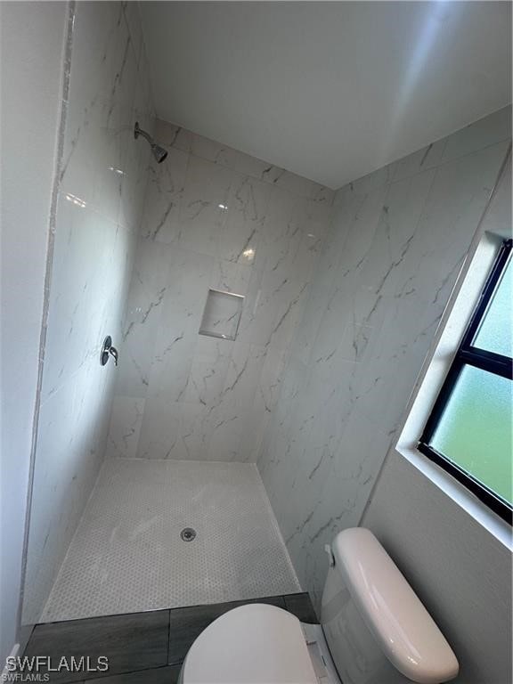 bathroom with tiled shower and toilet