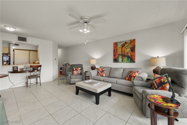 tiled living room with a textured ceiling and ceiling fan