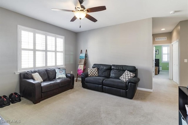 living area with light carpet, baseboards, visible vents, and a ceiling fan