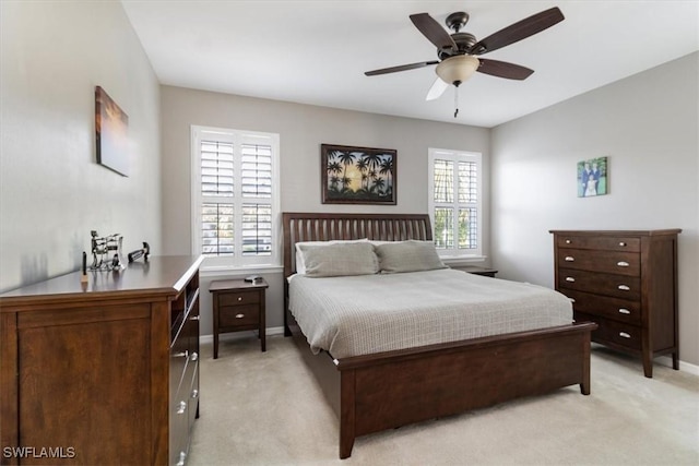 bedroom featuring a ceiling fan, light colored carpet, and baseboards