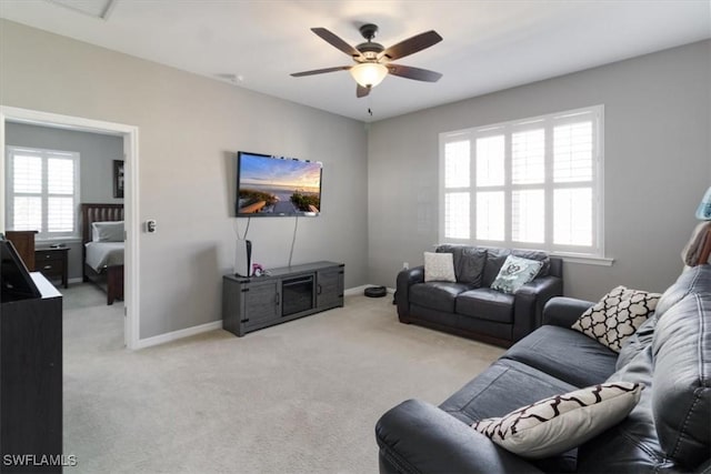 living area with light carpet, baseboards, and a ceiling fan