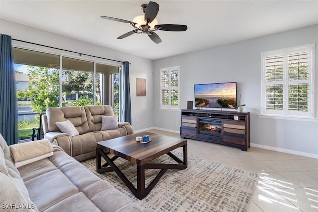 living area with ceiling fan, light tile patterned flooring, and baseboards