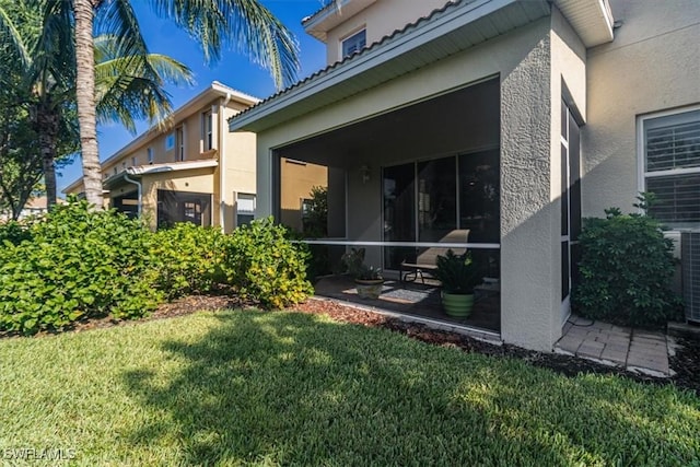 exterior space featuring a sunroom, a yard, and stucco siding