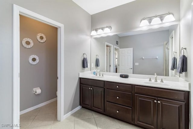 bathroom featuring double vanity, tile patterned flooring, baseboards, and a sink