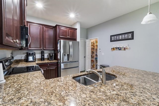 kitchen featuring light stone counters, recessed lighting, a sink, appliances with stainless steel finishes, and decorative light fixtures