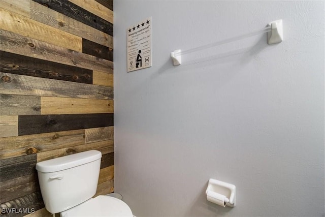 bathroom with wooden walls and toilet