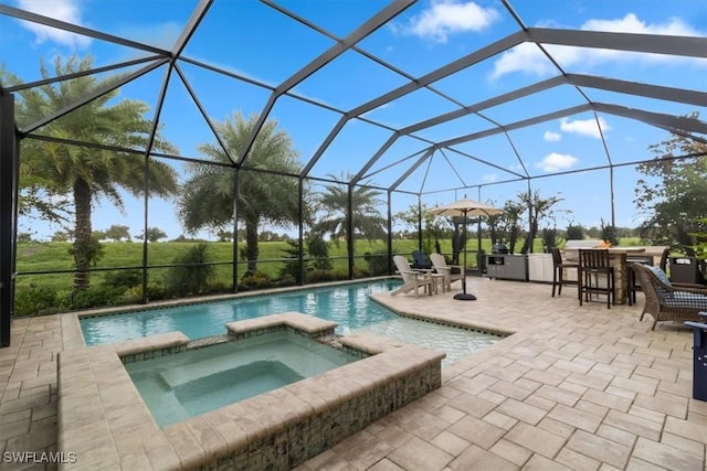 view of pool featuring glass enclosure, an in ground hot tub, exterior bar, and a patio