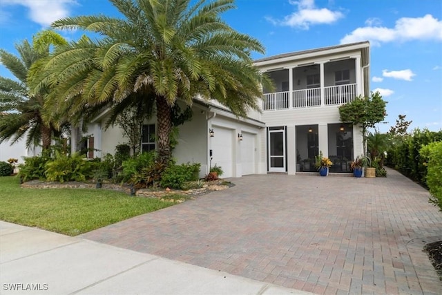 view of front of house with a front yard, a garage, and a sunroom