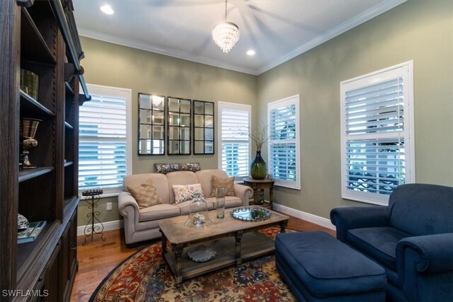 living area with a chandelier, wood-type flooring, and crown molding