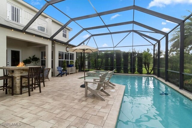 view of pool featuring a lanai, a patio area, an in ground hot tub, and an outdoor bar