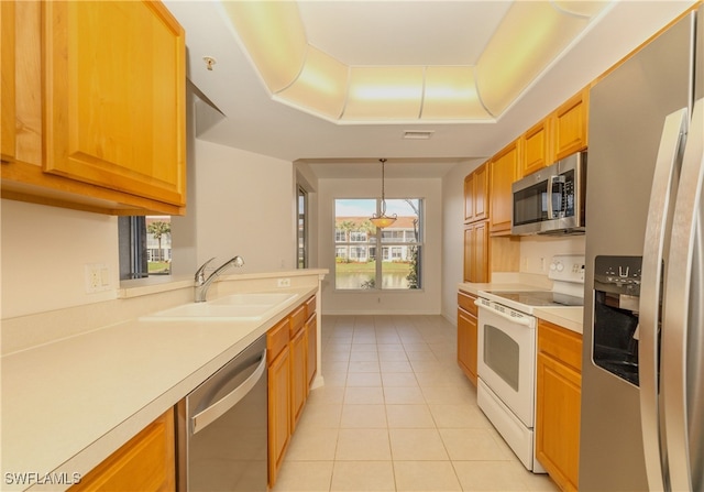 kitchen featuring a tray ceiling, appliances with stainless steel finishes, light tile patterned floors, sink, and decorative light fixtures