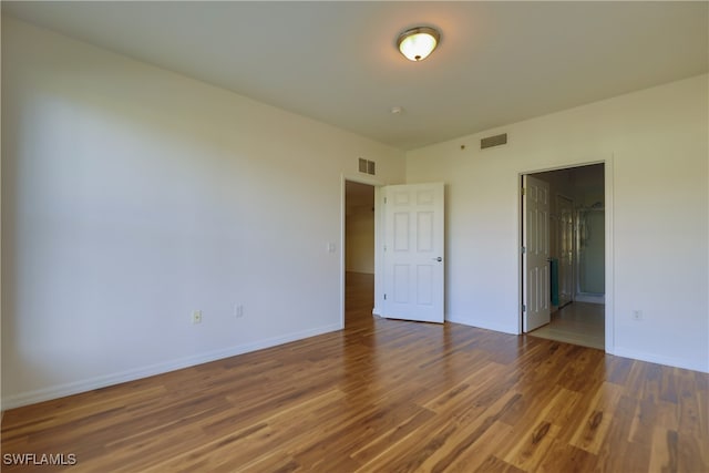 unfurnished bedroom with connected bathroom and hardwood / wood-style flooring