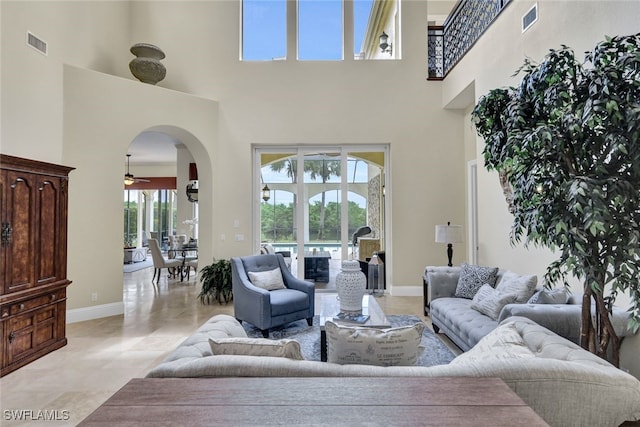 living room featuring a high ceiling, light tile patterned floors, a wealth of natural light, and ceiling fan