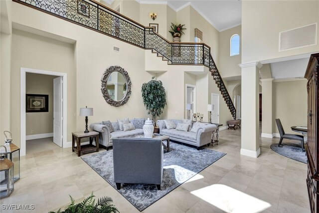 living room featuring ornate columns, a towering ceiling, and ornamental molding