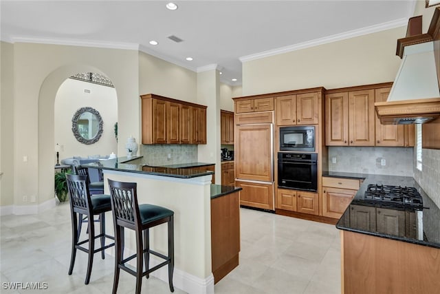 kitchen featuring premium range hood, crown molding, dark stone counters, and black appliances