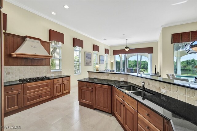 kitchen featuring custom exhaust hood, sink, dark stone counters, and gas stovetop