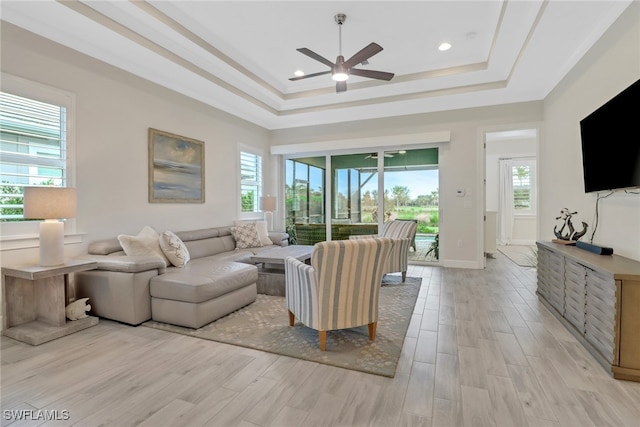 living room featuring light hardwood / wood-style floors, ceiling fan, and a raised ceiling