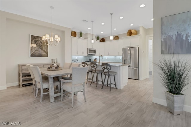 dining area with light hardwood / wood-style floors and an inviting chandelier