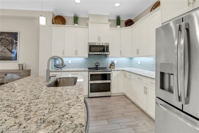 kitchen featuring stainless steel appliances, white cabinetry, light stone countertops, hanging light fixtures, and sink