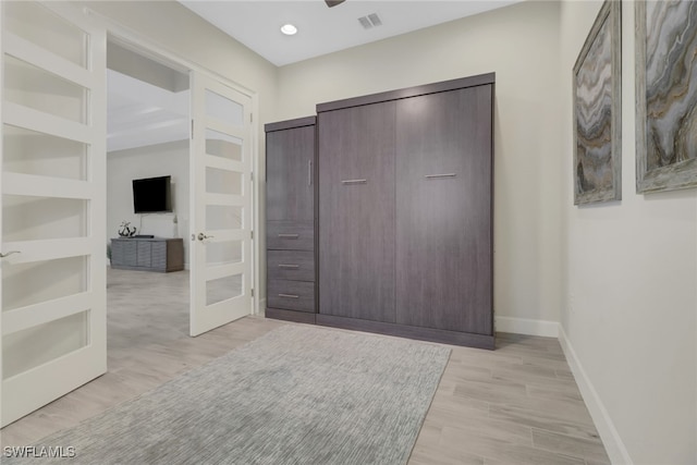 unfurnished bedroom featuring a closet, light wood-type flooring, and french doors