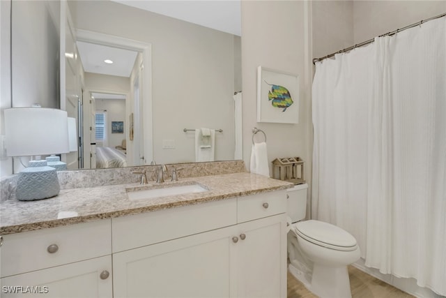 bathroom with hardwood / wood-style flooring, vanity, and toilet