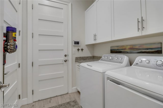 clothes washing area with cabinets, light wood-type flooring, and independent washer and dryer