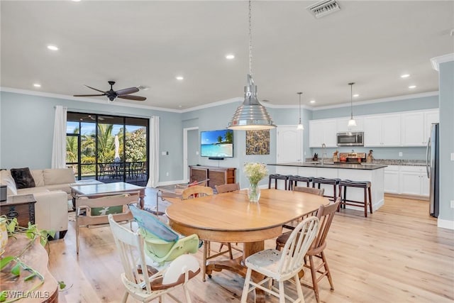 dining room with light hardwood / wood-style flooring, ornamental molding, and ceiling fan