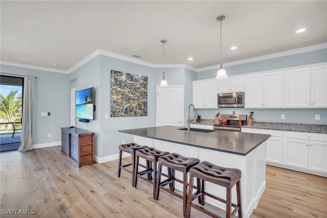 kitchen with decorative light fixtures, sink, white cabinets, a kitchen island with sink, and stainless steel appliances