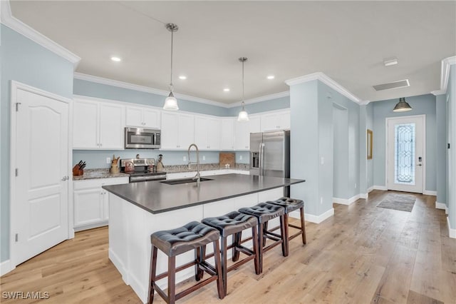 kitchen with appliances with stainless steel finishes, sink, a center island with sink, and white cabinets