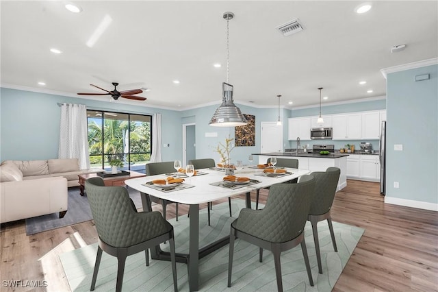 dining space with crown molding, sink, and light wood-type flooring