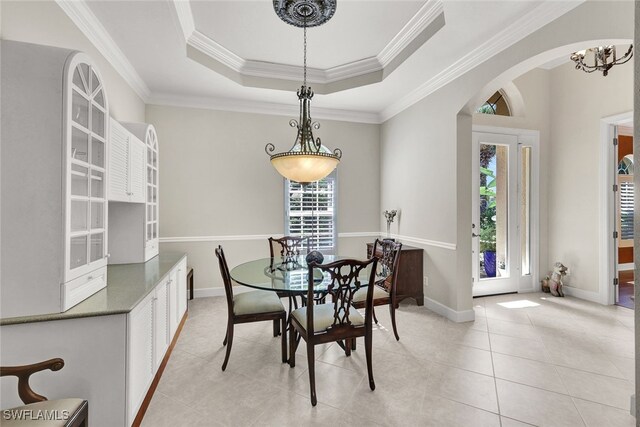 tiled dining area with a raised ceiling and crown molding