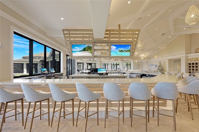 bar with high vaulted ceiling, hanging light fixtures, and light stone counters