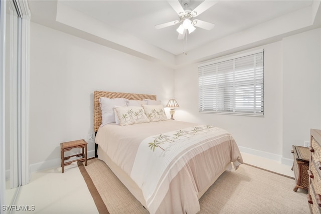 carpeted bedroom featuring a tray ceiling and ceiling fan