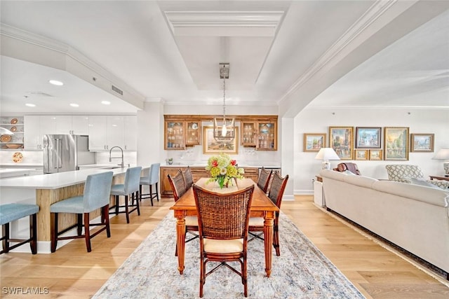 dining room featuring sink, crown molding, and light hardwood / wood-style flooring