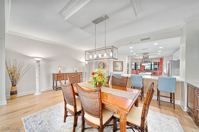 dining area featuring crown molding, decorative columns, and light wood-type flooring