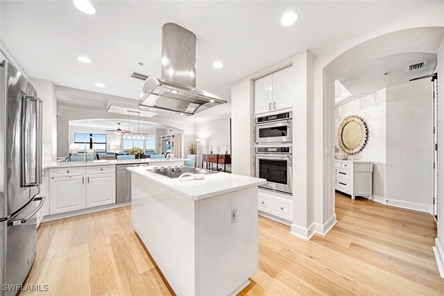 kitchen featuring white cabinets, light wood-type flooring, island range hood, and stainless steel appliances