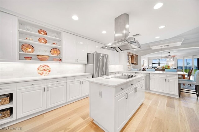 kitchen with appliances with stainless steel finishes, a kitchen island, white cabinetry, and island exhaust hood