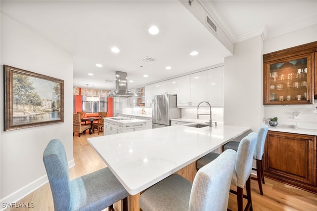 kitchen with island exhaust hood, high quality fridge, light hardwood / wood-style flooring, white cabinetry, and kitchen peninsula