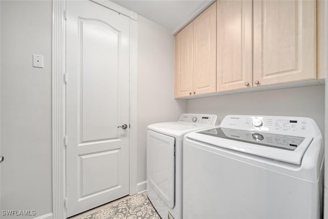 clothes washing area featuring washer and clothes dryer and cabinets