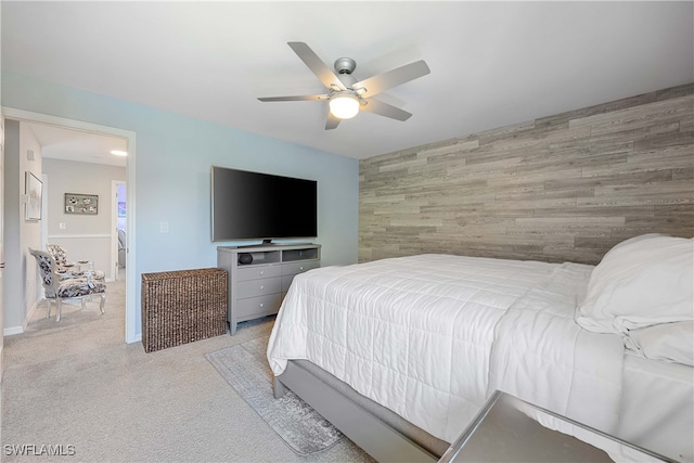 bedroom featuring ceiling fan, light carpet, and wood walls