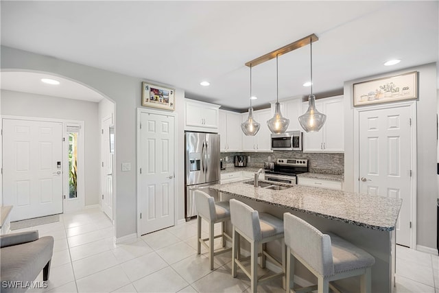 kitchen with appliances with stainless steel finishes, light stone countertops, tasteful backsplash, hanging light fixtures, and white cabinets