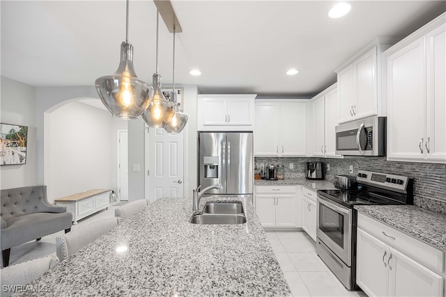 kitchen with backsplash, white cabinets, appliances with stainless steel finishes, light tile patterned floors, and sink