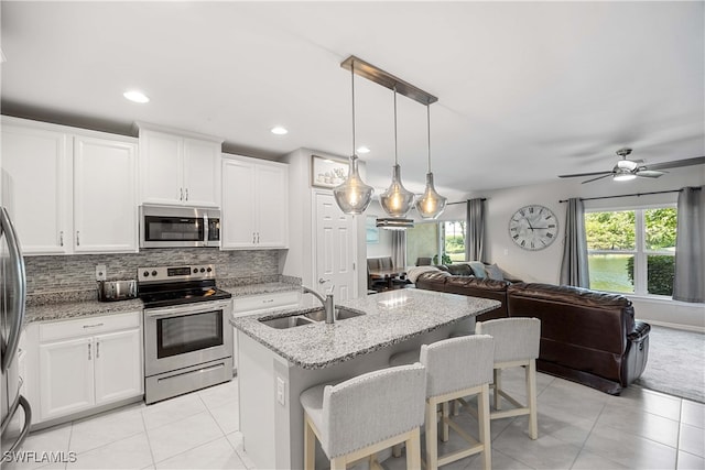 kitchen featuring appliances with stainless steel finishes, tasteful backsplash, sink, ceiling fan, and light tile patterned flooring