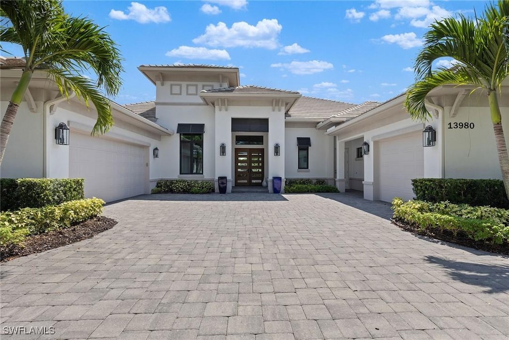 view of front of house with a garage, decorative driveway, a tiled roof, and stucco siding