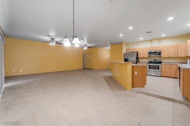 kitchen featuring hanging light fixtures, light tile patterned floors, a center island, appliances with stainless steel finishes, and ceiling fan with notable chandelier