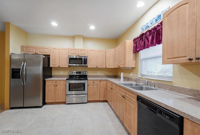 kitchen with stainless steel appliances, sink, light tile patterned floors, and light brown cabinetry