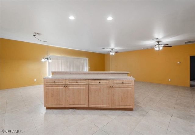 kitchen featuring ceiling fan with notable chandelier, pendant lighting, light stone countertops, and light brown cabinetry