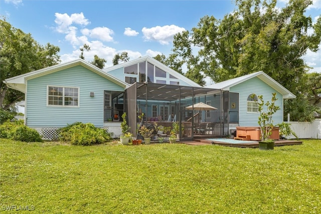 back of house featuring a hot tub, a deck, and a lawn