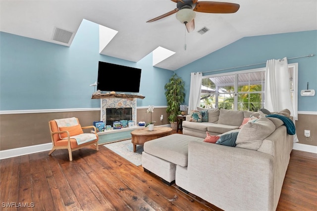 living room with vaulted ceiling with skylight, ceiling fan, and hardwood / wood-style floors